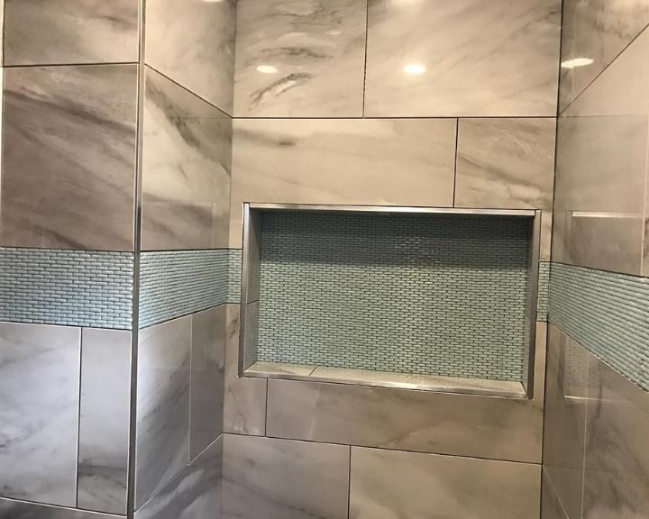 A bathroom with a glass shower door and tiled walls.