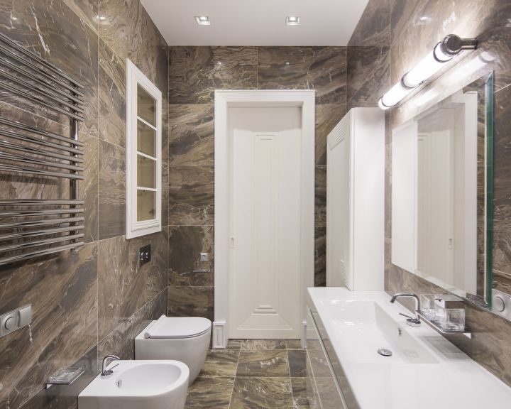 A bathroom with marble walls and a toilet, perfect for a bathroom remodel.
